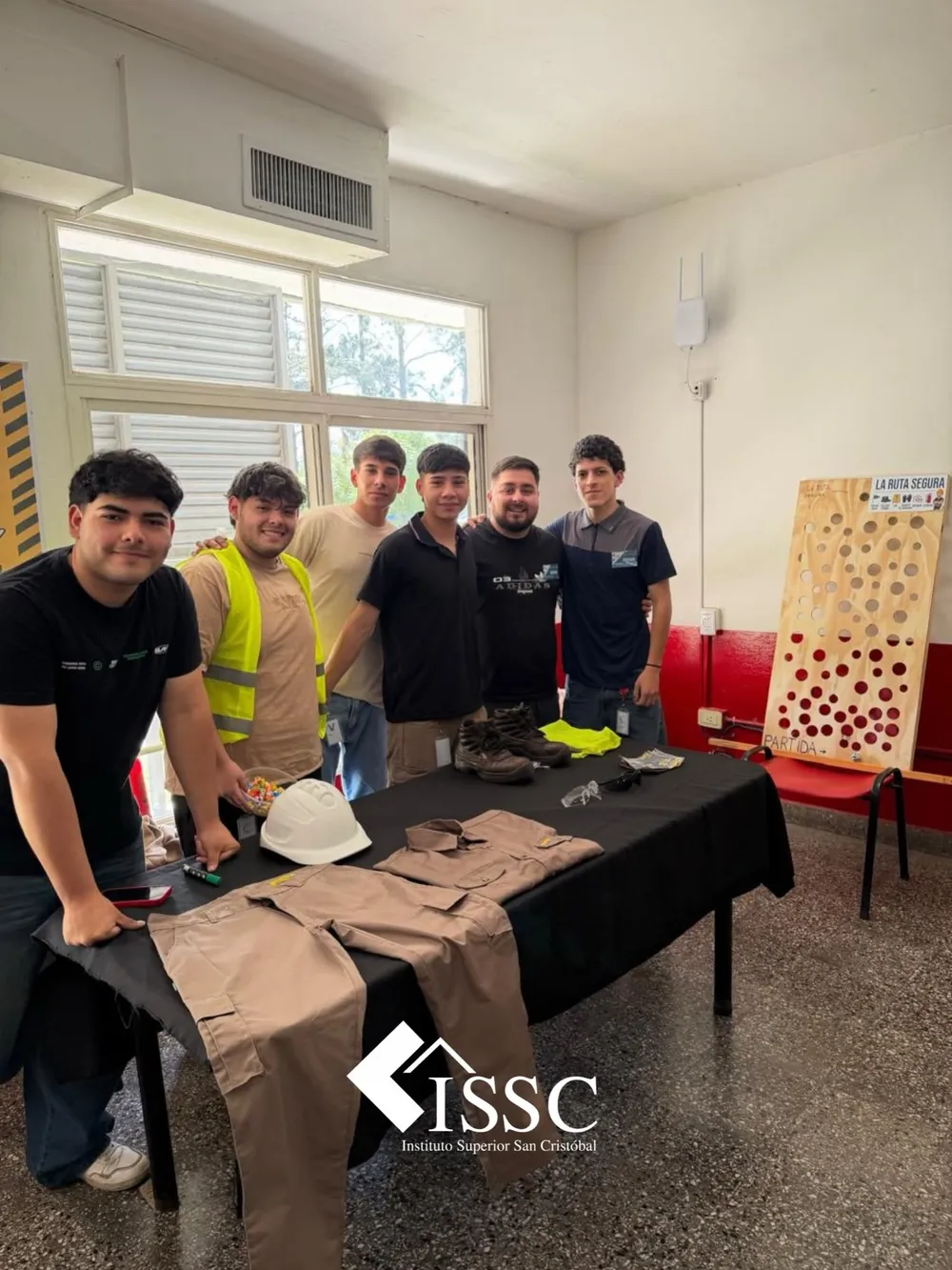 Estudiantes junto a una mesa con casco, calzado, guantes y otros elementos de protección personal